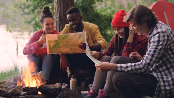Cinemagraph döngü - erkek ve kadın arkadaş turist ateşi etrafında oturan ve haritalar ormanda yürüyüş sırasında yaz aylarında eğitim vardır. İnsanlar rahat giysiler giyiyor. — Stok video