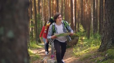 Yakışıklı olan harita tutarak ve arkadaşları onu iz ahşap boyunca takip ediyorlar iken ormanda yürüyüş. Seyahat, yaz ve yönlendirmesi kavramı.