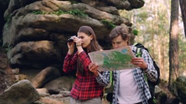 Çift ormanda duruyor, adam harita üzerinde kız dürbün ile arıyorsunuz o zaman ilginç yer arkadaşı için gösterilen ve gülüyor.