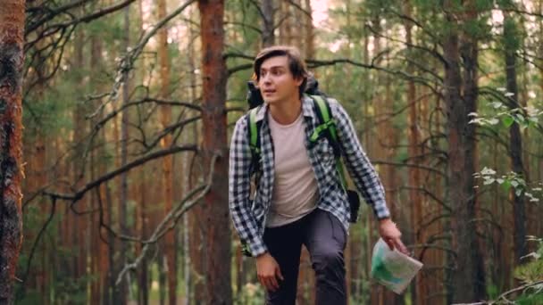 Beau jeune homme voyageur marche dans la forêt puis debout et regardant la carte à la recherche de la bonne voie puis s'en va. Concept Personnes, voyages et aventures . — Video