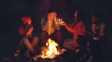 Heyecanlı turist genç adam Doğum günü pasta giving onu tebrik, adam kapalı gözlerle dilek yapıyor ve mumlar üfleme, arkadaşları eller alkışlar.