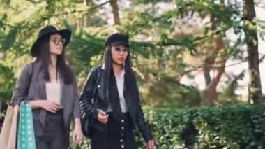 Güzel kızlar hipsters kağıt torbalar ile sokakta yürürken ve güneşli sonbahar günde şehirde konuşuyor. Birlikte, arkadaşlık ve eğlence kavramı alışveriş.