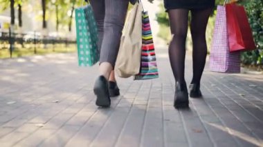 Düşük açılı renkli kağıt torbalar ile sokakta mağazalar yoğun günün ardından yürüyen kadın bacaklar bir kadeh. Genç insanlar, alışveriş ve dostluk conccept.