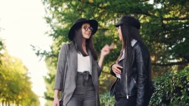 Mutlu kız sohbet ve ayakta açık havada parlak alışveriş torbaları gün alışveriş merkezinde tartışırken tutan kaldırımda gülüyor. Kadınlar şık giyim ve gözlük takıyorsun.