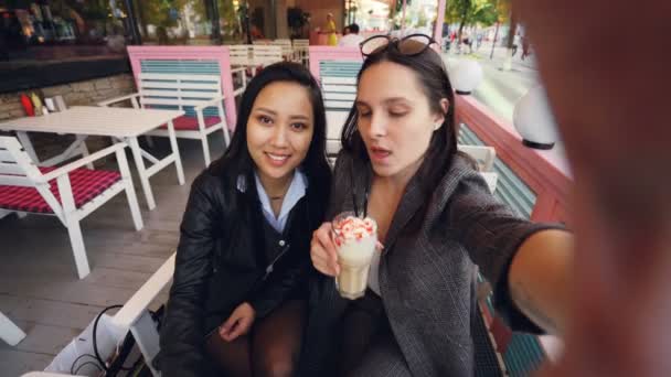 Punto de vista de toma de fotos de mujeres jóvenes guapas tomando selfie es café sentado en la mesa con cócteles beber y posar divirtiéndose y abrazándose. Concepto de personas, bebidas y fotos . — Vídeo de stock