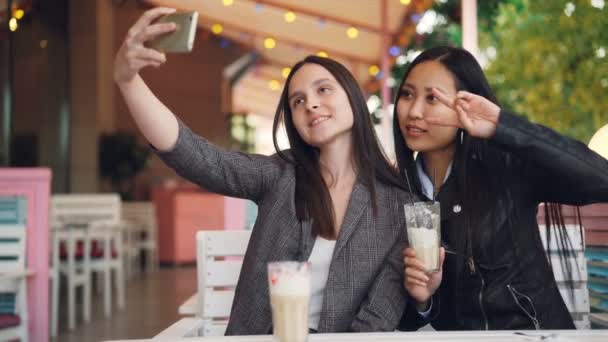 Chica Atractiva Está Tomando Selfie Con Amiga Asiática Sentada Café — Vídeos de Stock