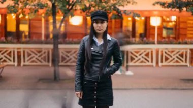 Yalnız Asyalı kadın sokakta geç akşam ayakta dışında ve sonra terk bekleyen kameraya bakarak, hızlandırılmış uzaklaştırma. İnsanlar hızlı bir şekilde geçerek.