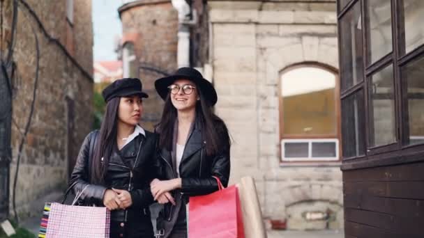 穿着时髦衣服的快乐女孩们在城市的大街上散步 背着购物袋 在秋天的时候谈论社交活动 谈话和时尚概念 — 图库视频影像