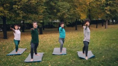 Genç kadın savaşçı poz Virabhadrasana ayakta sonra üçgen Trikonasana Park açık sınıf sırasında pozisyon yoga yapıyoruz. Gençlik ve sağlık kavramı.