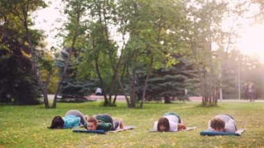 Grup Genç bayanlar sonbahar gününde park açık havada yoga pratik, esnek kızlar paspaslar üzerine test etmektir. İnsan, Doğa ve eğlence kavramı.