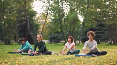 Kadın yoga öğrenciler öğretim üyesi ile germe egzersizleri yapıyor Park açık sınıf sırasında güzel kadın. Rahat kızlar uygulama üzerinde yoğunlaşmıştır.