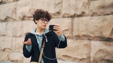 Şık genç bayan görüntülü arama online, konuşma yapıyor ve ekran giyen kulaklık el smartphone kullanarak ve bakarak. Konuşma, teknoloji ve insan kavramı.