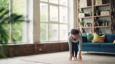 Güzel kız giyim evde yoga yapıyor sonra ile dinlenme spor Namaste eller. Büyük pencere ve modern mobilyalar şık çatı stil iç görülür.