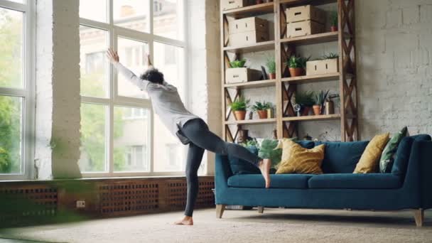 Istruttore di yoga femminile sta praticando da solo a casa facendo complesso di asana in piedi sul pavimento e corpo in movimento. Attività sana, auto-sviluppo e appartamenti concetto . — Video Stock