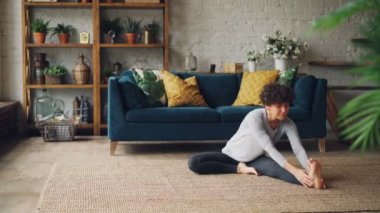İnce genç kadın ileri bir bacak için bükme sonra ayakkabıcılar poz evde yoga pratik sırasında rahatlatıcı. Sağlık, gençlik ve spor genel kavram.
