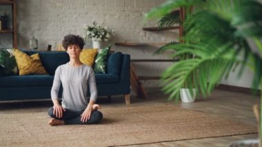 Rahat genç bayan poz yangın günlük Agnistambhasana içinde daire katta oturan ve evde yoga pratik sırasında nefes. Millennials ve spor kavramı.