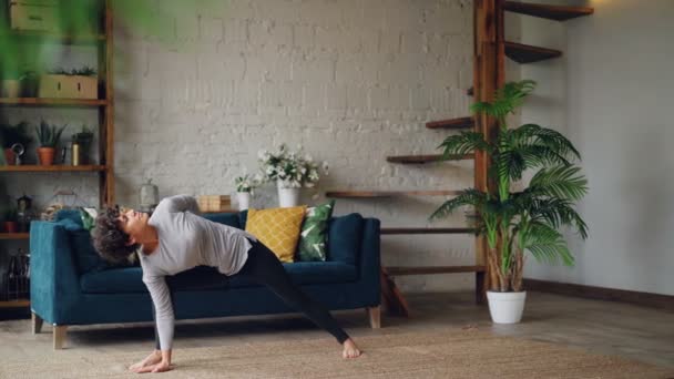 Smal ung kvinna gör sekvens av hatha yoga asanas ensam hemma njuter av personlig träning och ensamhet. Aktiv ungdom och självutveckling koncept. — Stockvideo