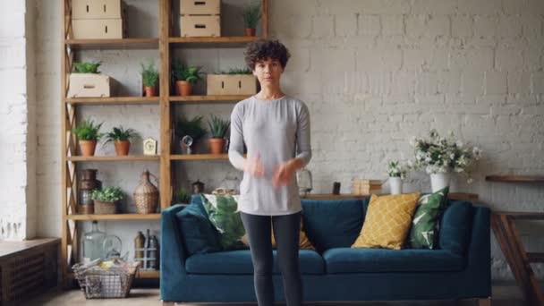 Portrait of cheerful girl yoga teacher recording video for her vlog demonstrating Tree position and Namaste, speaking and smiling looking at camera. — Stock Video