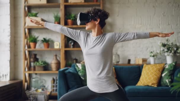 Aantrekkelijke persoon doet opeenvolging van yoga asanas kunstmatige realiteit bril tijdens persoonlijke training thuis. Sport, entertainment en interieur concept. — Stockvideo