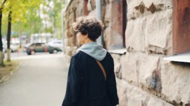 Ağır çekim sonra dönüm, kameraya bakıyor ve gülümsüyor cadde boyunca yürüyüş güzel ince kız portresi. Genç insanlar, eğlence ve şehir kavramı.