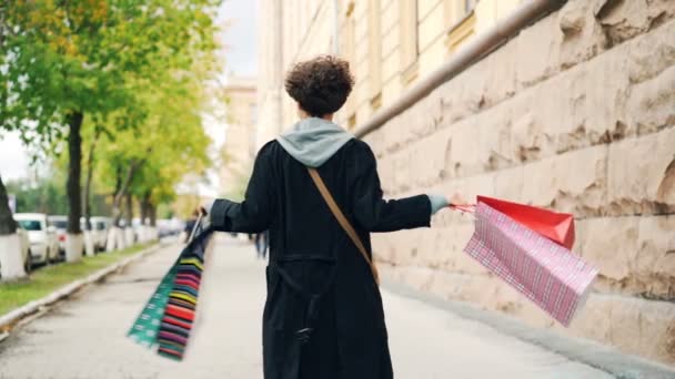 Zpomalený pohyb portrét vzrušená dívka drží dárkové tašky a otáčel kolem pohledu na kameru bavit. Nakupování, mládež životní styl a moderní koncept bydlení.