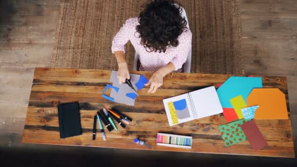 Vue de dessus de la jeune créatrice travaillant dans le bureau à la maison faire du collage à partir de chiffres de coupe de papier éclaboussures et de les coller dans un carnet. Art et concept de travail . — Video