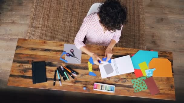 Vista dall'alto di una donna impegnata a disegnare figure di carta incollate nel taccuino usando colla-stick che lavora da sola a casa. Creatività, design e concetto di arte moderna . — Video Stock