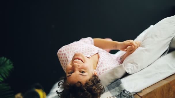 Retrato en cámara lenta de mujer despreocupada en ropa casual rodando en cama doble divirtiéndose y mirando a la cámara. Hora de dormir, buen humor y concepto de los millennials . — Vídeos de Stock