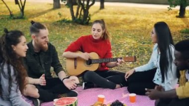 Çok ırklı grup arkadaşıyla gitar çalmak, şarkı ve ekose park ve zevk eğlence ve iyi bir şirket'ın bahçesinde oturup içki zevk olduğunu.