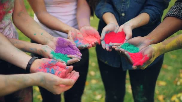 Close shot of peoples hands holding colorful paint powder for Indian traditional Holi festival standing outdoors. National culture, fun and holiday concept. — Stock Video