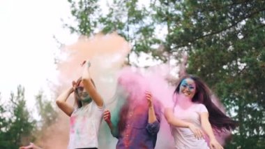 Yavaş hareket insanlar renkli un içinde park açık havada partide atar iken toz boya bulutlarda dans mutlu genç bayanlar. Duygu ve tatil kavramı.