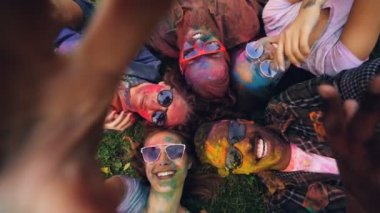 Parti Holi festival ve video kayıt cihazı ile kamera tutarak selfie alarak arkadaşlarınızla çim üzerinde yalan mutlu kadın bakış açısı shot. Eğlenceli ve dostluk kavramı.