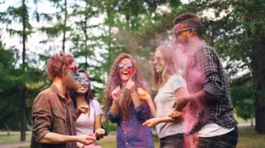 Partide dans ve toz boya atma o zaman parlak toz bulutlarda gülüyor kadın ve neşeli gençlik erkek ağır çekim. Mutluluk ve tatil kavramı.