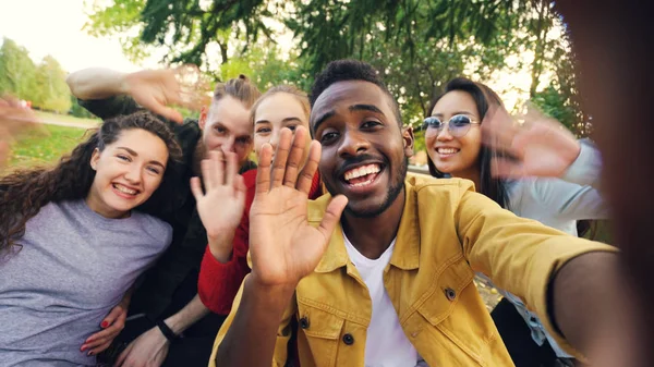 Point of view shot of cheerful students making online video call calling friends holding device looking at camera and talking gesturing waving hands — Stock Photo, Image