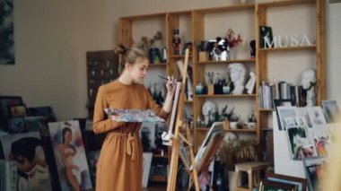 Güzel kız ressam workroom paleti ve fırça tutan ve tuval arayan yalnız çalışıyor. İşgal, yaratıcı Gençlik ve çalışma alanı kavramı.