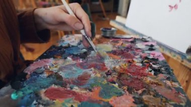 Yetenekli sanat öğrencisi profesyonel kadın öğretmeni onun iş yerinde arıyor iken çiçek tuval üzerine resim paletindeki renkleri karıştırma. Yaratıcılık ve eğitim kavramı.