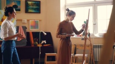 Çekici kız öğrenci Studio sanat dersi sırasında resim, onun öğretmeni geliyor ve onun öğretim öğüt vermek yardım. Sanat ve araçları ile rahat atölye görülür.