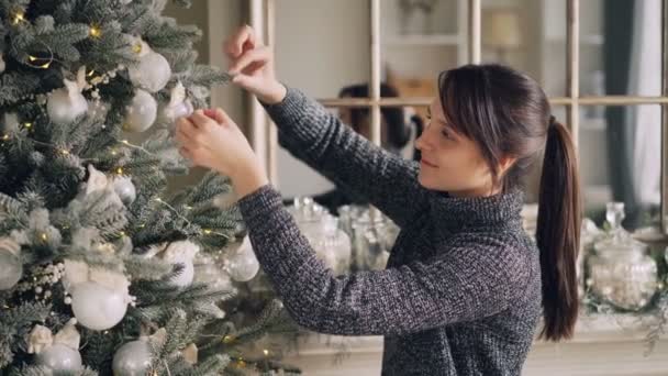 Креативна Брюнетка Прикрашає Зелену Різдвяну Ялинку Торкаючись Красивих Кульок Готуючись — стокове відео