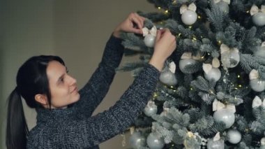 Gülümseyen güzel kız yılbaşı ağacı Noel günü dokunmadan önce gümüş toplar dekorasyon ve zevk şenlikli durum ışıkları. İnsanlar ve tatil kavramı.