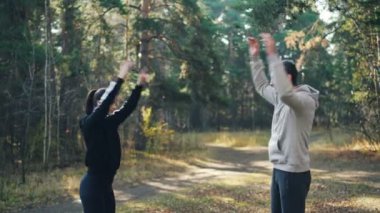 Adam genç çift ve kadın kolları twirling ve keyfini ısınma ve iyi bir şirket gülümseyen park açık havada spor yapıyorsun. Doğa, eğitimler ve sağlıklı yaşam konsepti.