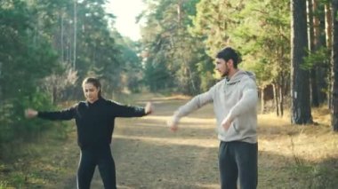 Sevimli kız parkta spor bilek ve silah eğitimi sıcak güneşli günde birlikte sırasında ısınma sevgilisi ile yapıyor. Ruhsal sağlık ve hobi kavramı.