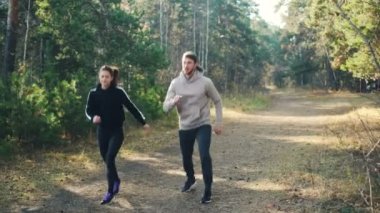 Mutlu çift genç kadın ve kocası yere atlama ve gülümseyen Park spor yapıyoruz. Aktif yaşam tarzı, modern Gençlik ve doğa kavramı.