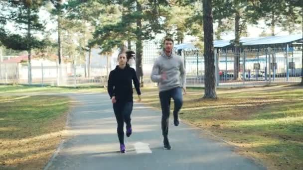 Schönes Paar hübsches Mädchen und bärtiger Kerl trainieren im Park zusammen Laufen und Springen. Aktiver Lebensstil, gesunde Jugend und Freizeitkonzept. — Stockvideo