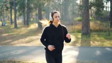 Şirin esmer Park'ta jogging ve yalnız pratik Kulaklığımda dinlerken Dolly vurdu. Modern teknoloji, sağlık ve eğlence kavramı.