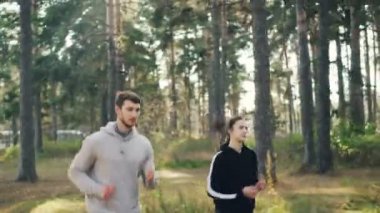 Spor giyim etkin arkadaşlar sağlıklı faaliyet ve sonbahar doğa tadını güneşli günde parkta koşu. Herdem yeşil çam ağaçlarının arka planda görülebilir.