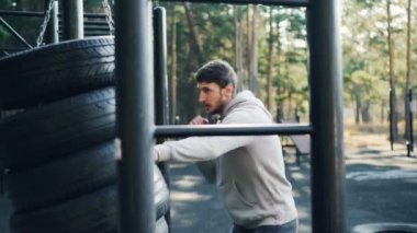 Güçlü sakallı adam boks yalnız açık havada lastik spor-yere yaz gününde egzersiz sırasında kullanarak. Aktif Gençlik ve doğa kavramı dışında egzersiz.