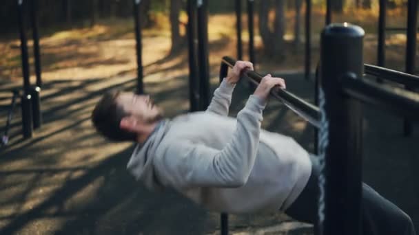 Skäggig kille utövar utomhus göra pull-ups på låg räck i park i höst morgon utbildning ensam. Aktiv livsstil och sport koncept. — Stockvideo