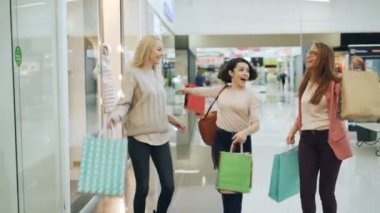 Mutlu kız grup alışveriş kağıt torbalar ile yürüme, gülen ve vitrinler mal işaret dans merkezindeki eğleniyor. Gençlik ve shopaholics kavramı.