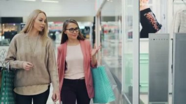 Modern alışveriş merkezi windows yürüyüş o zaman el hareketi ve tartışmak iç çamaşırı yeni koleksiyon seyir çekici genç bayanlar sohbet.