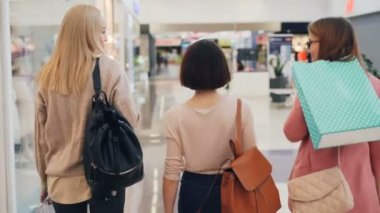 Mutlu genç kadın arkadaşlar birlikte alışveriş parlak torba tutarak ve hafta sonu konuşurken yürüyüş mesafesindedir. İletişim, gençlik ve dostluk kavramı.